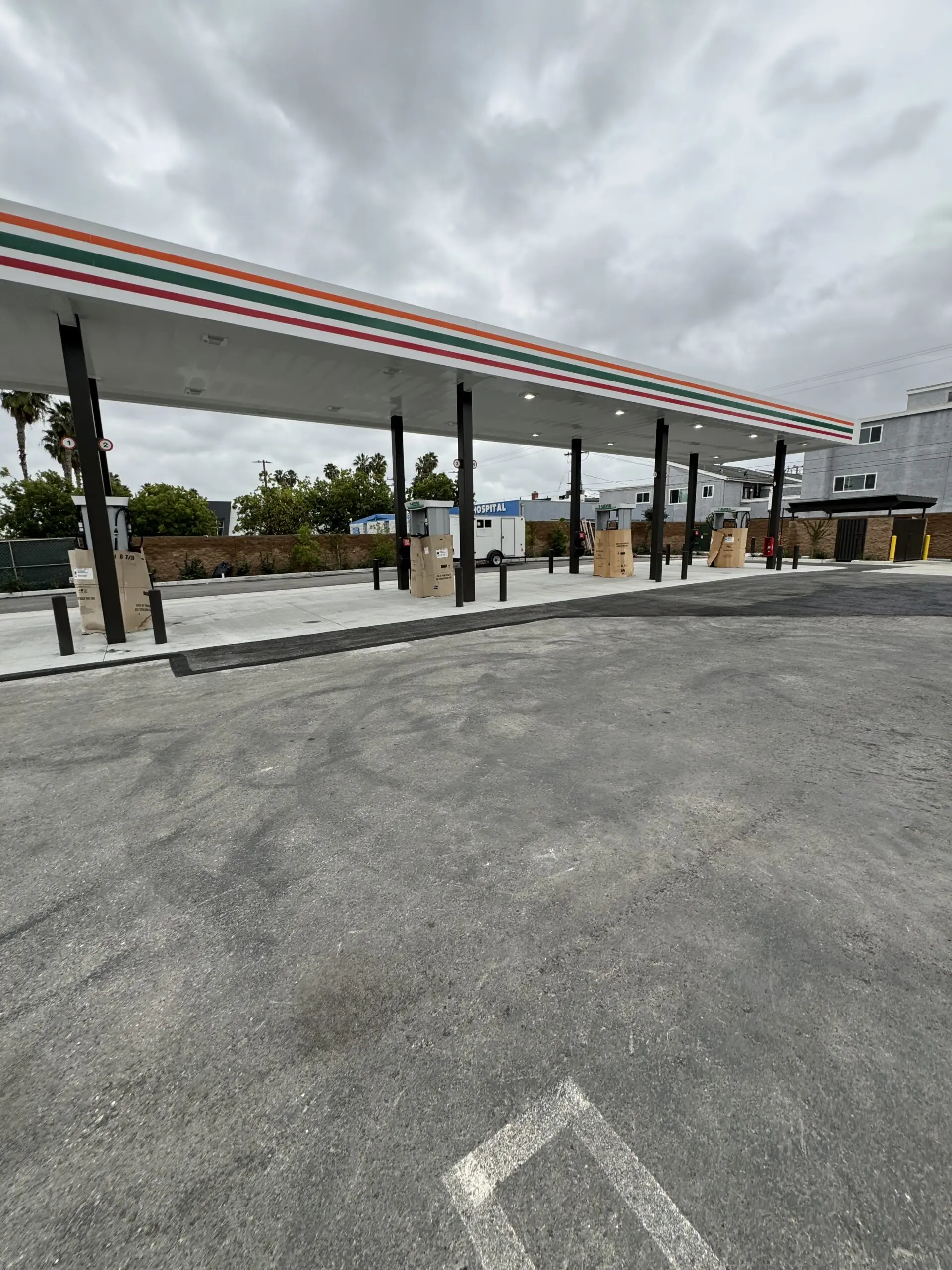 Gas station with a lot of cars parked in front of it, surrounded by buildings, trees
