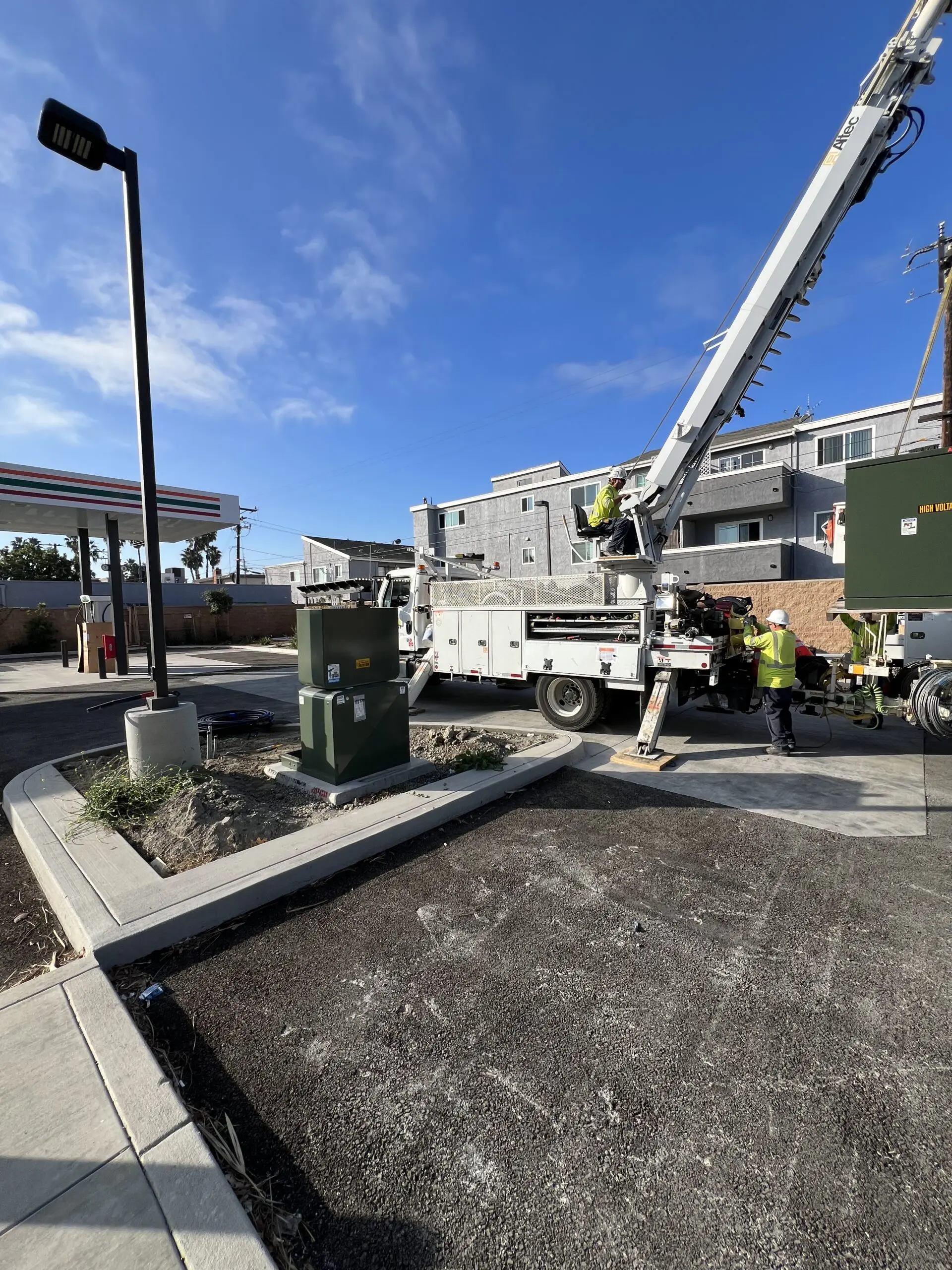 Man in a cherry picker working on a street light in front of a gas station