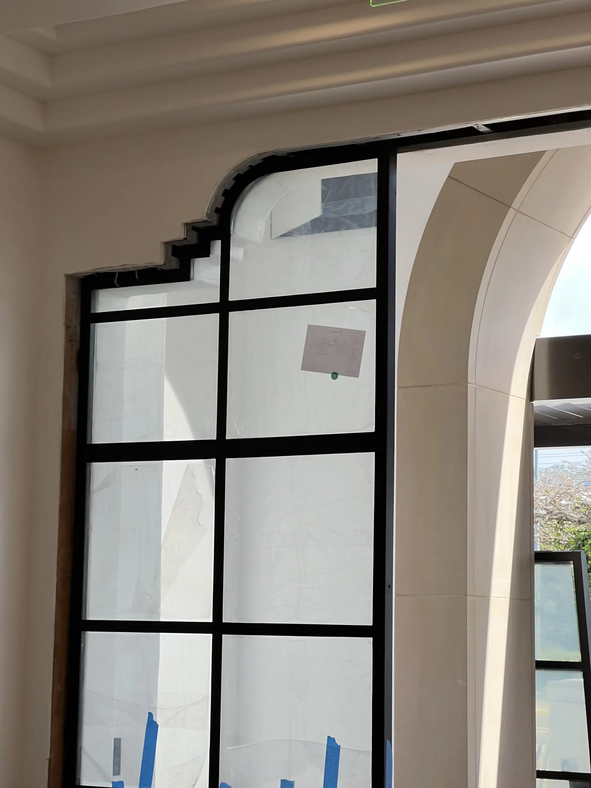 Large window in the corner of a room with a white wall, a glass door