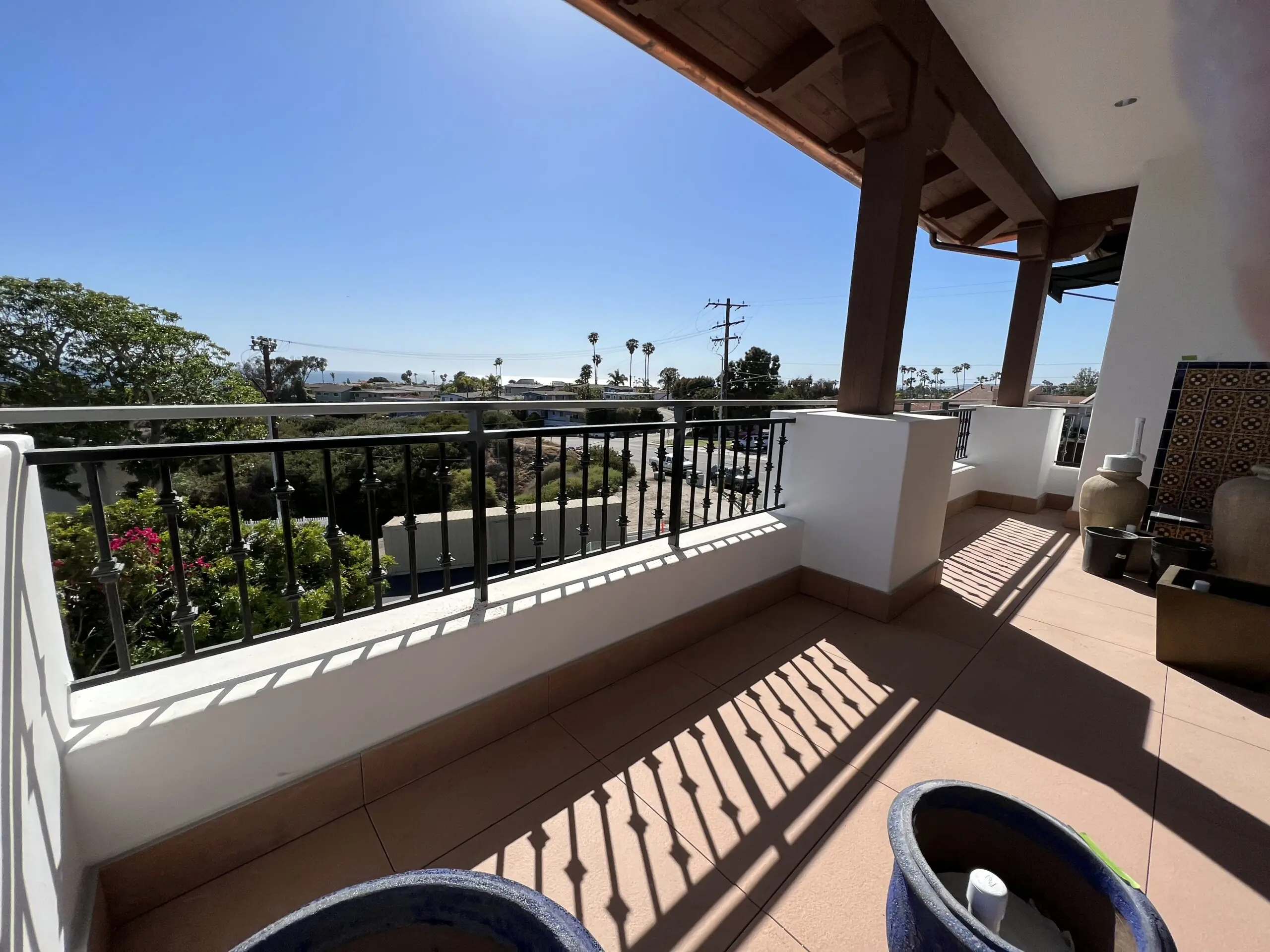 Balcony with two potted plants on it, overlooking a view of the ocean