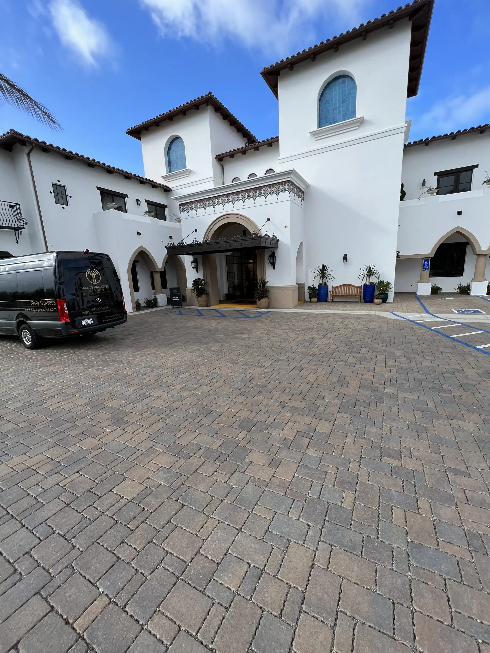 Black van parked in front of a white building with windows, arches, pillars and a roof
