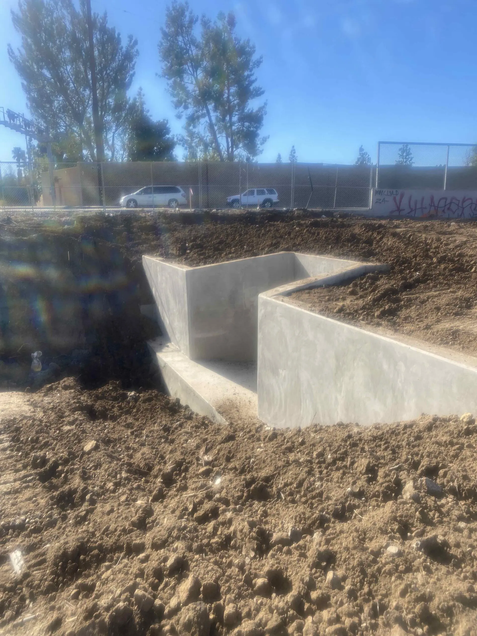 Construction site with a lot of dirt and a fence, where a concrete foundation is being built