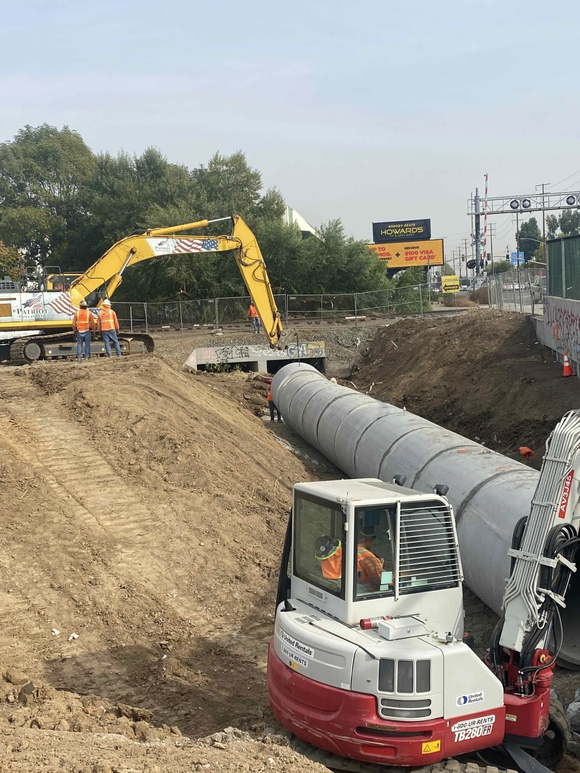 Construction site with a large pipe being built on the side of a road