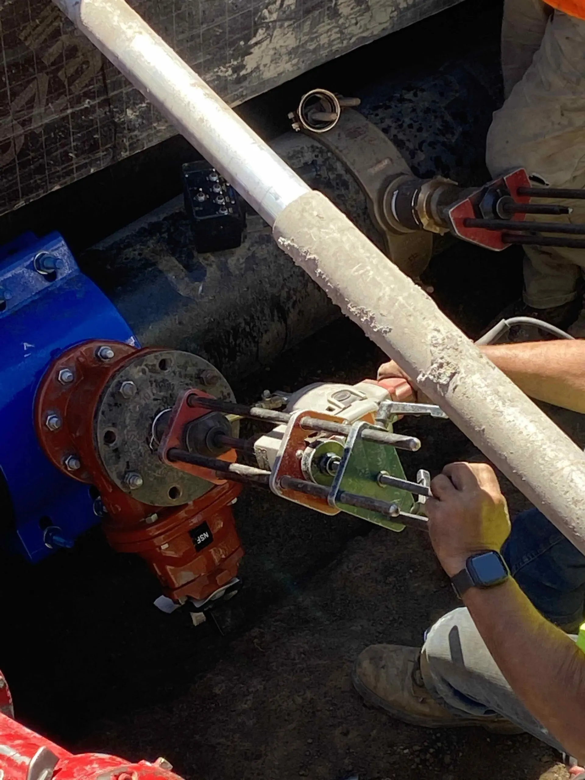 Two men working on a pipe in a construction site