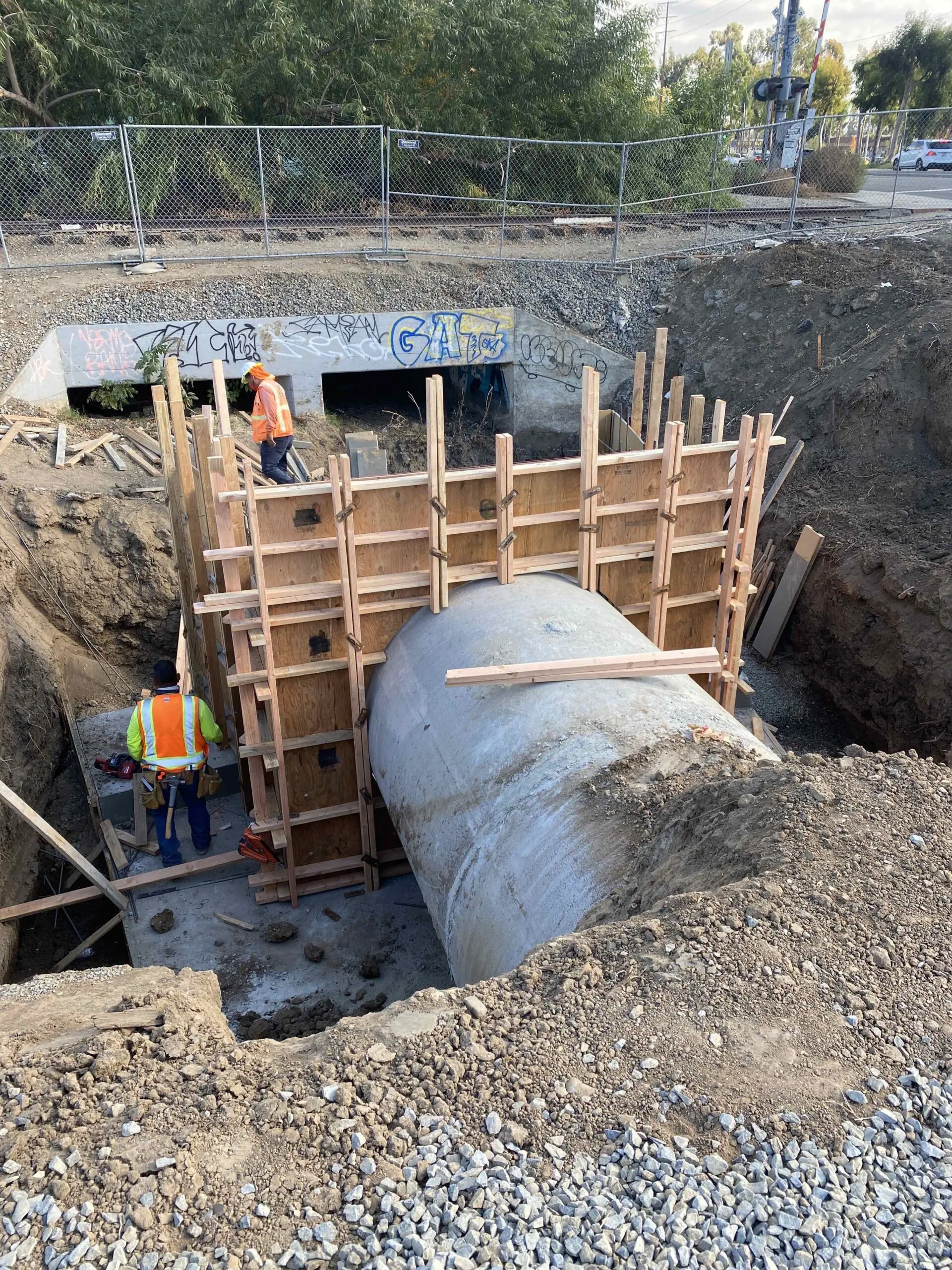 Two men working on a construction site with a large pipe in the middle of it