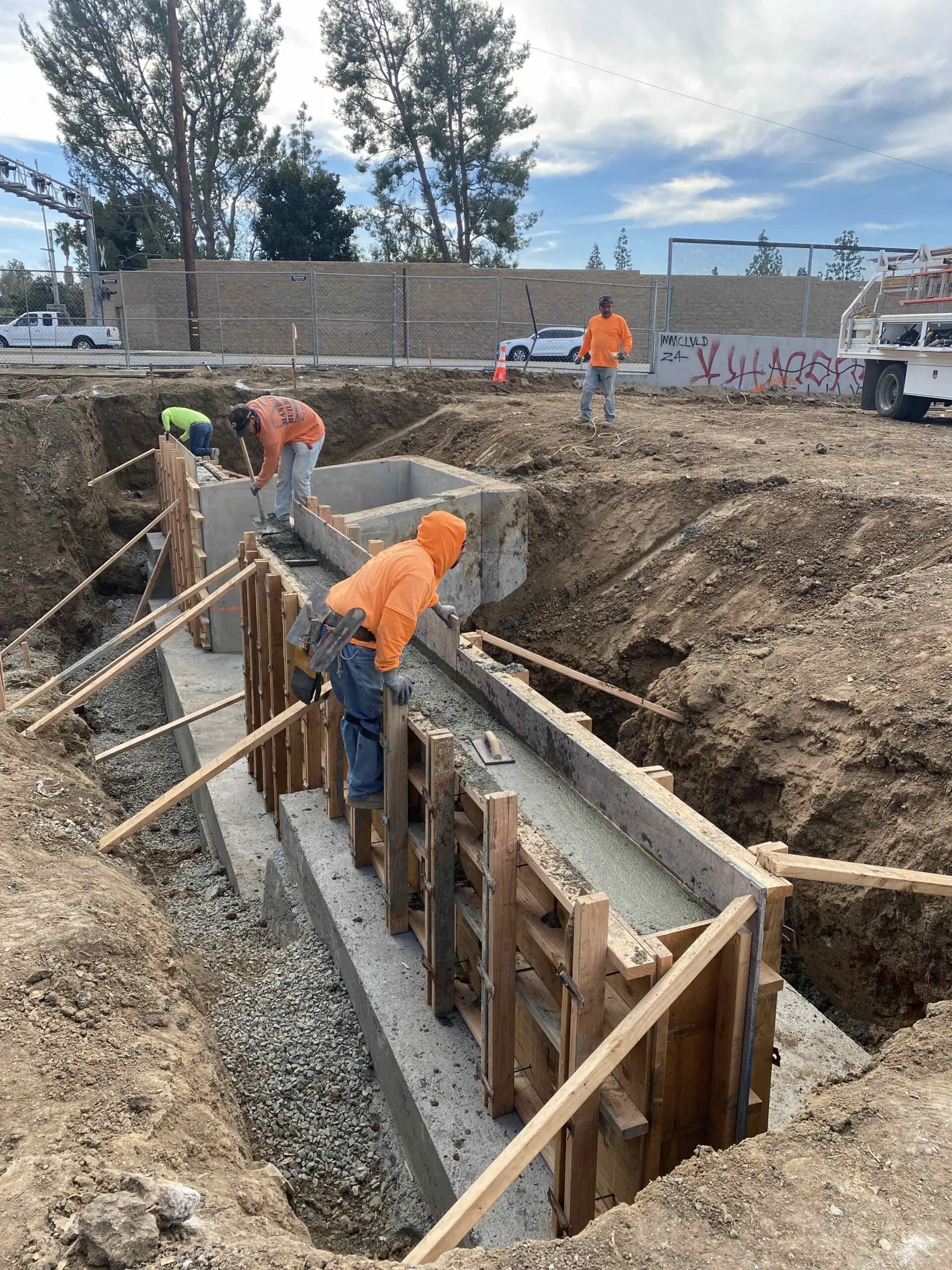 Group of men working on a construction site in the city of Sacramento, are wearing orange jackets