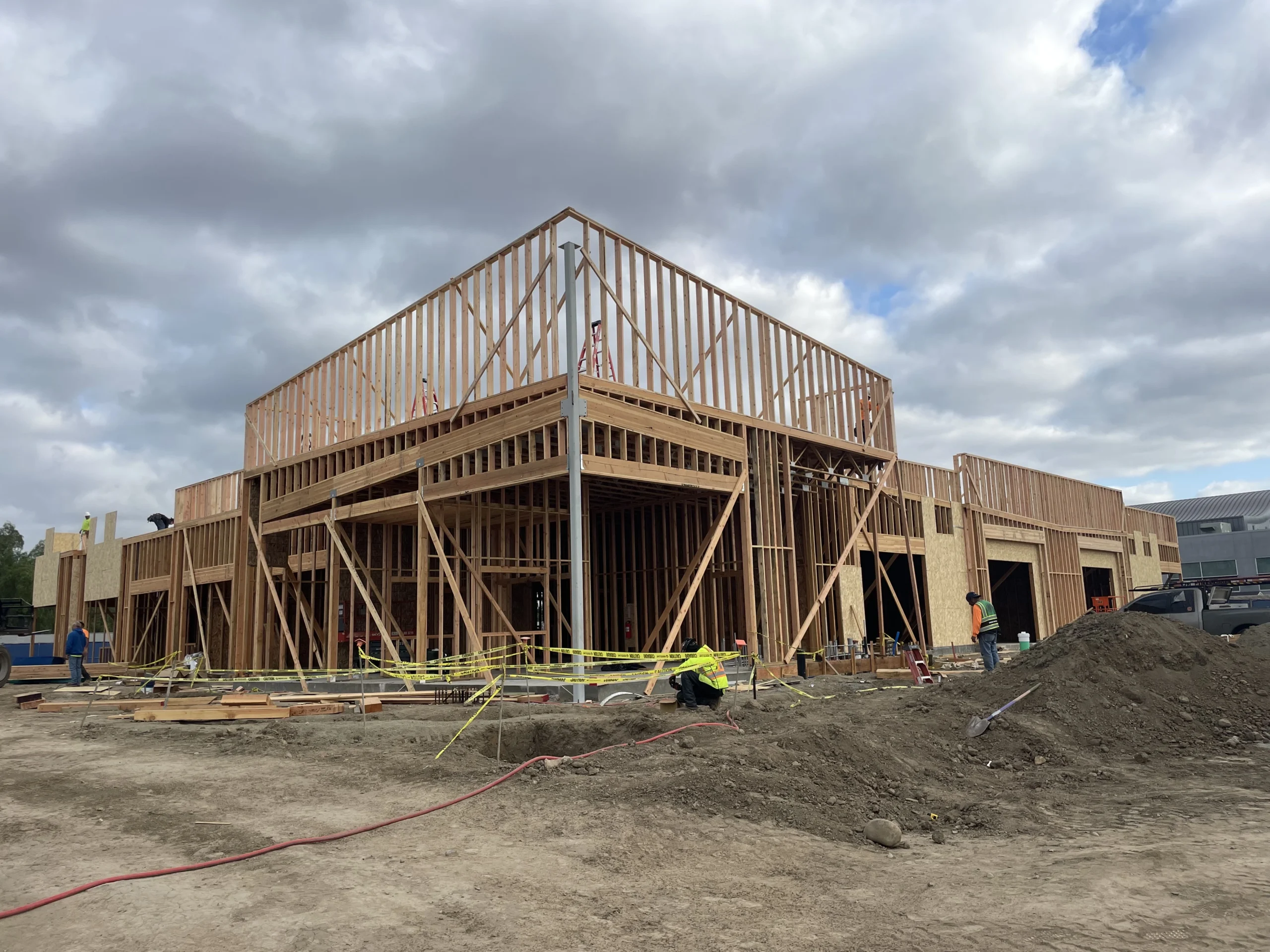 Construction site with a large house under construction in the middle of it