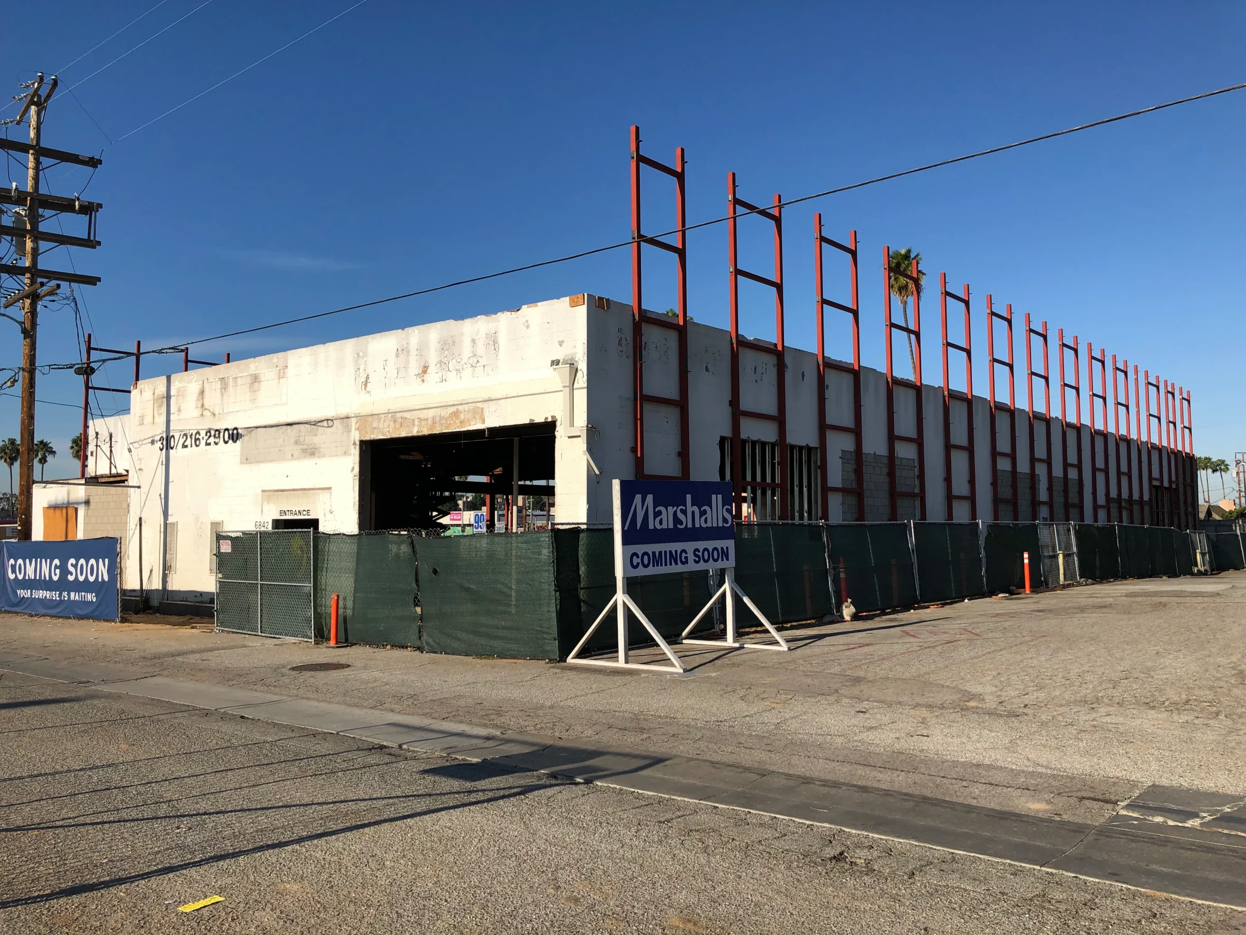 Building under construction on the corner of a street, with a sign that reads "Marshalls" in front of it