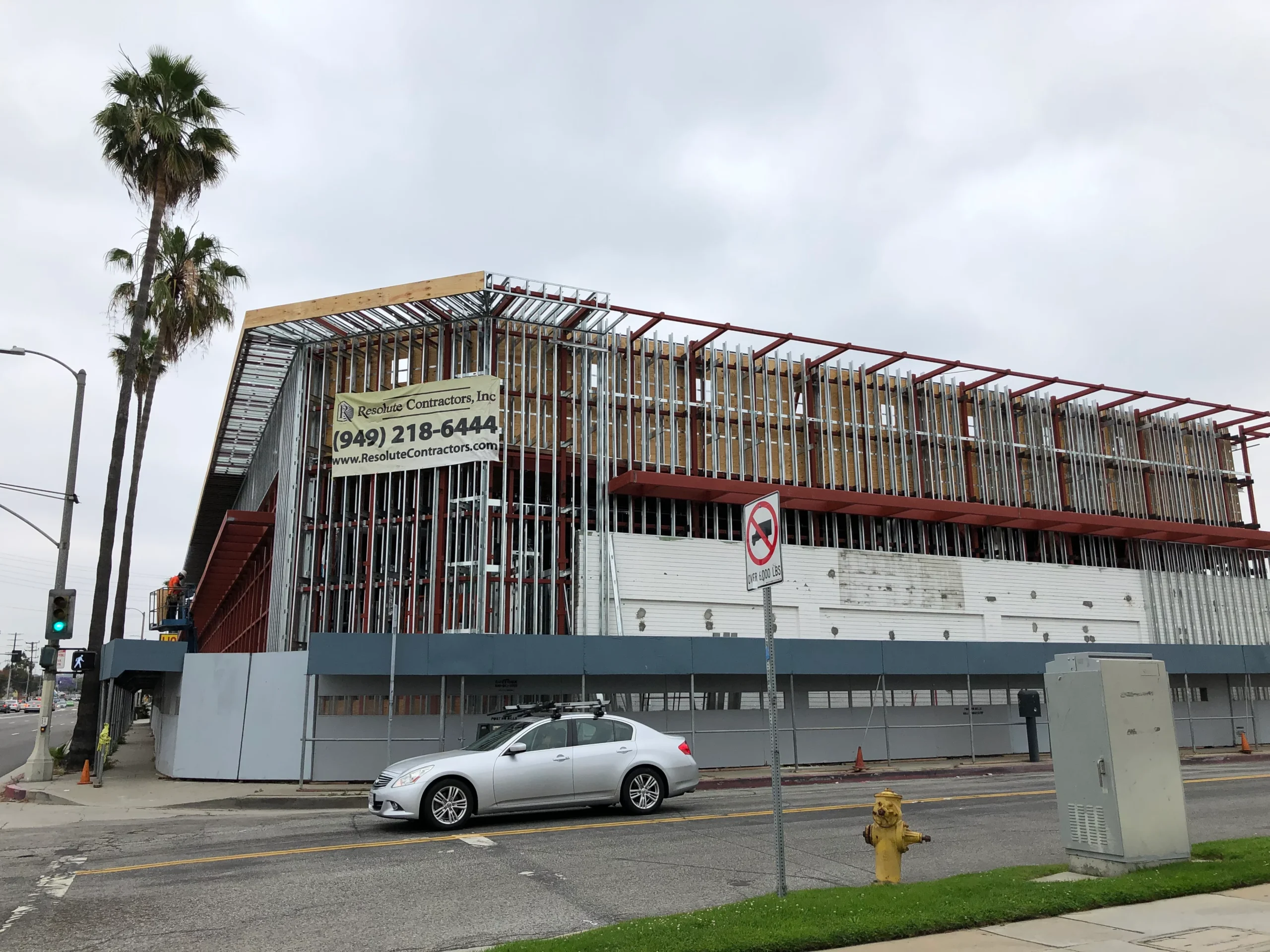 Car parked in front of a building under construction on the corner of a street